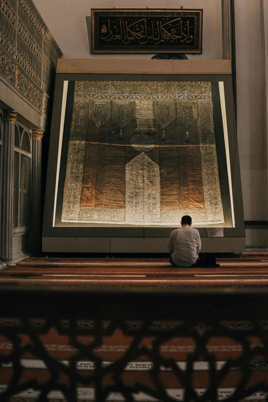 a man sitting on the ground in front of a large picture