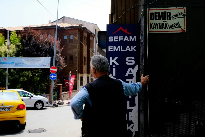man holding a sign that says seifam emlakk
