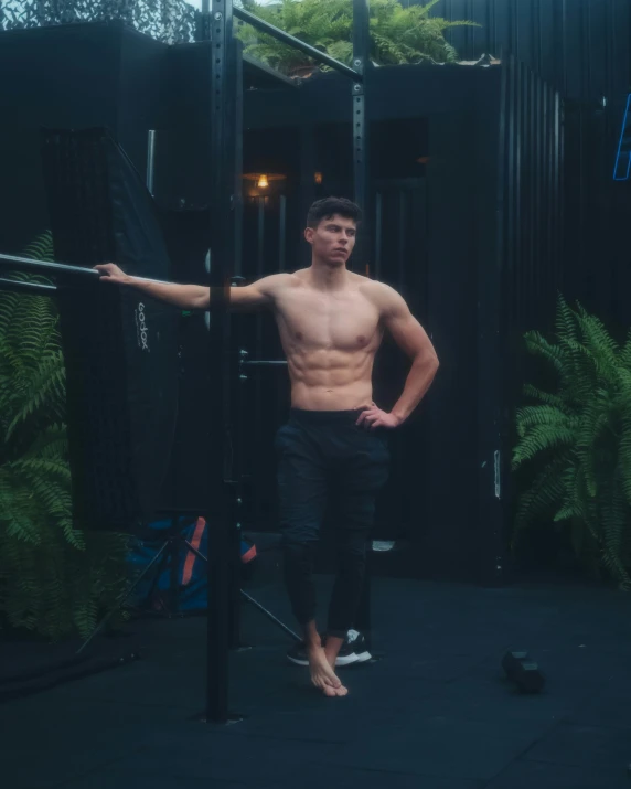 shirtless young man holding hands on bars inside gym