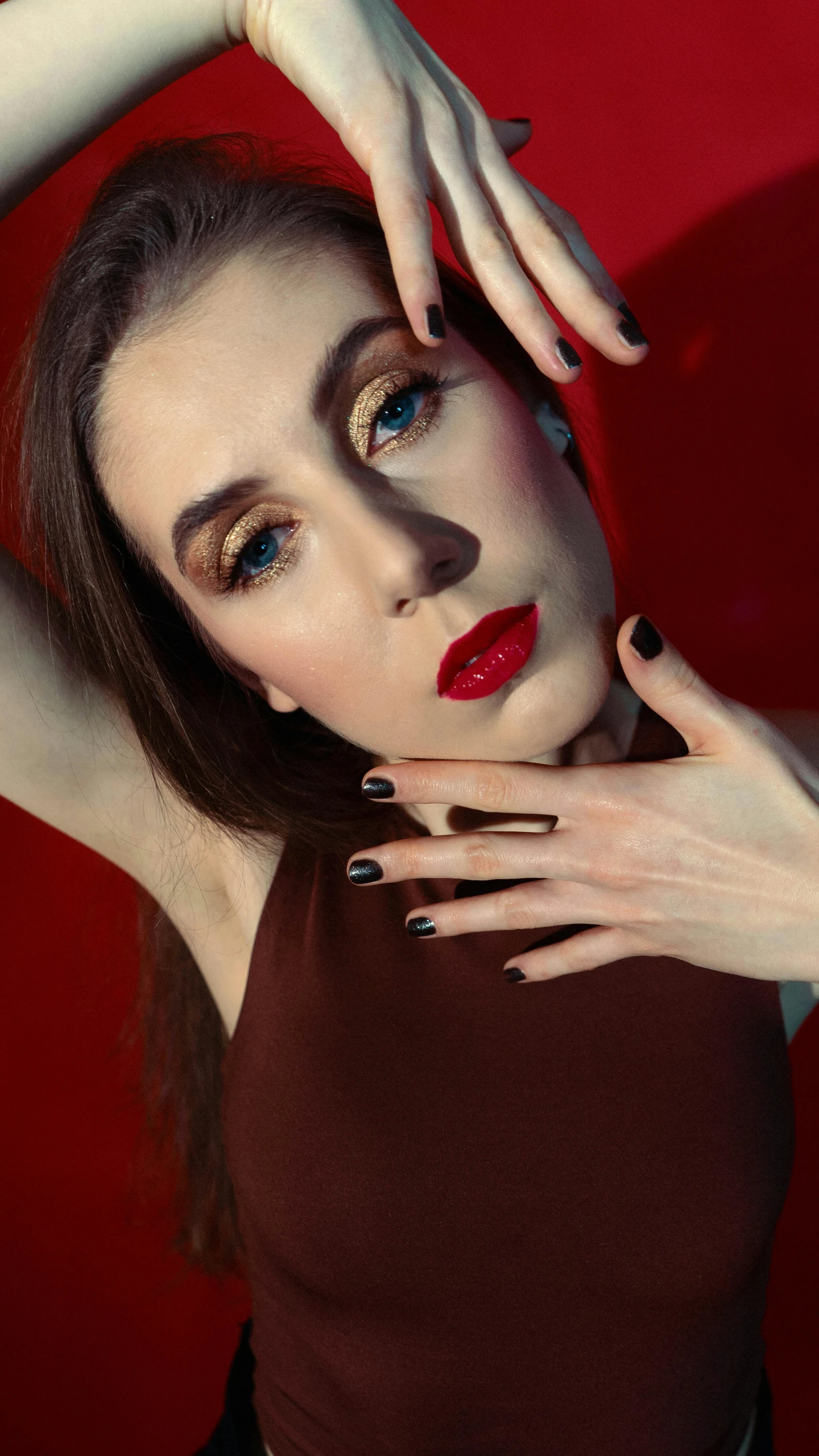 a woman in black and gold has her hand near her head