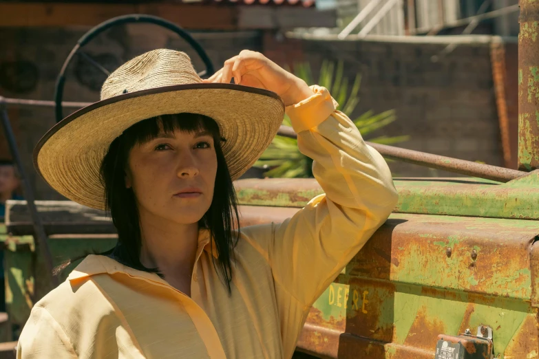 woman in white hat standing near tractor, looking to the side