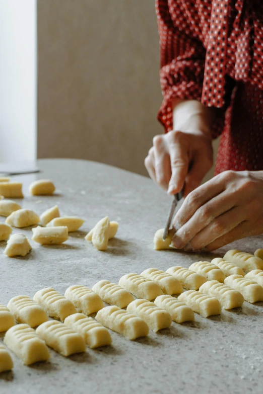 a woman is  small white cakes that are arranged into rows