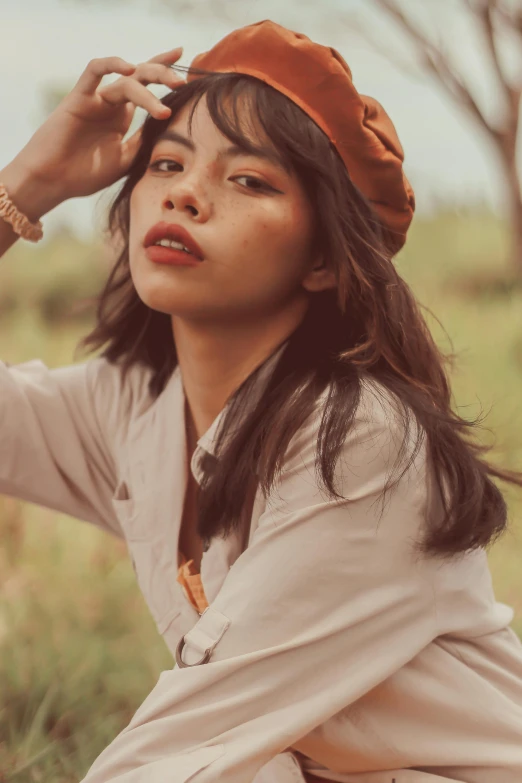 a young woman wearing a hat sits in the grass