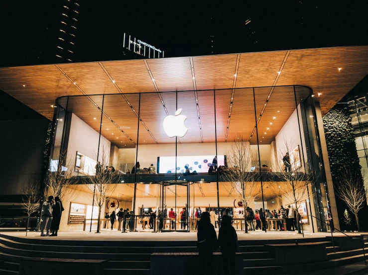 people are gathered outside of a large apple building