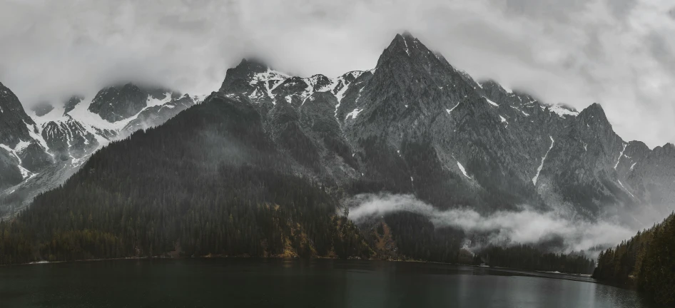 snowy mountains rise above the water and trees