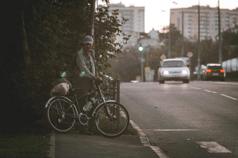 the man is leaning against the post near his bicycle