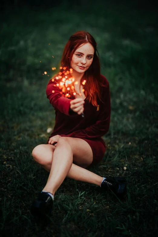 a woman kneeling down with sparklers in her hands