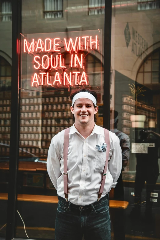 a man with suspenders and a hat standing in front of a store