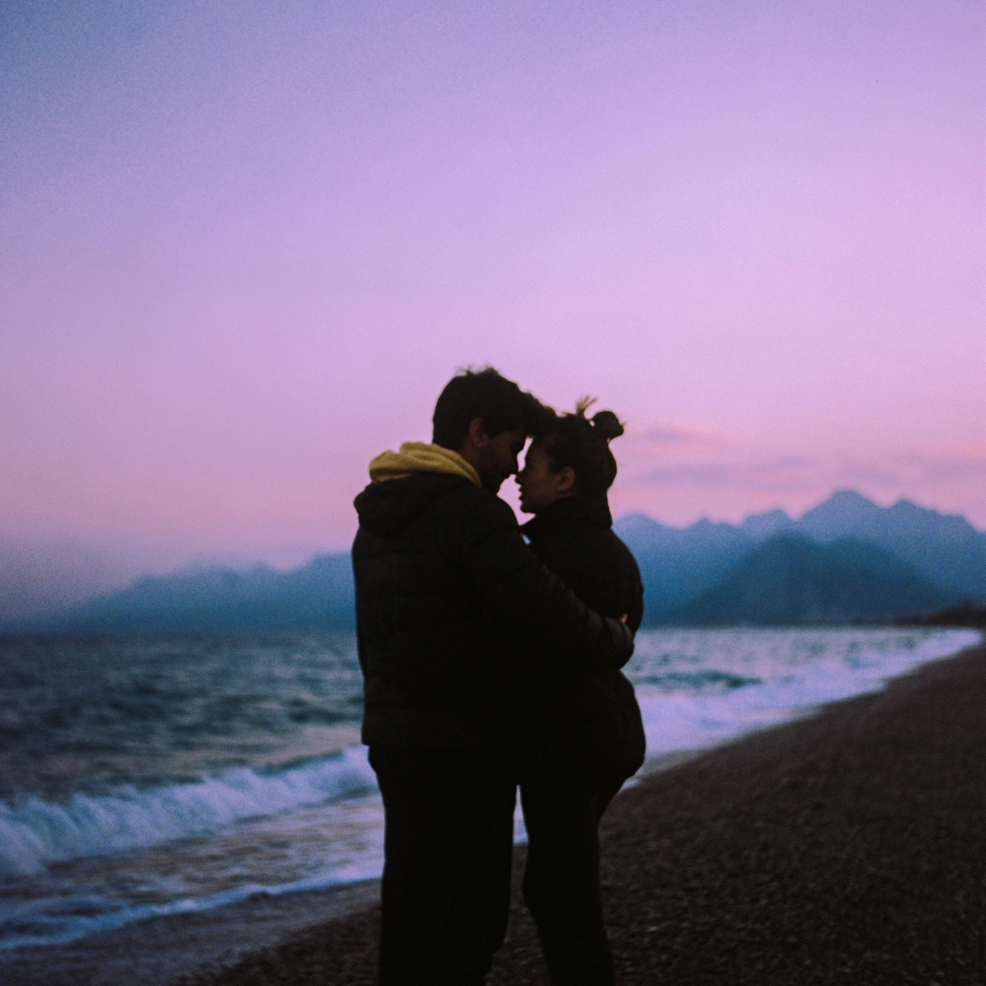 a couple of people standing next to the ocean