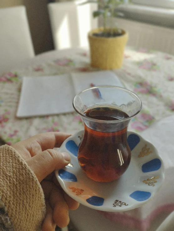 a hand holding a tea cup sitting on top of a plate