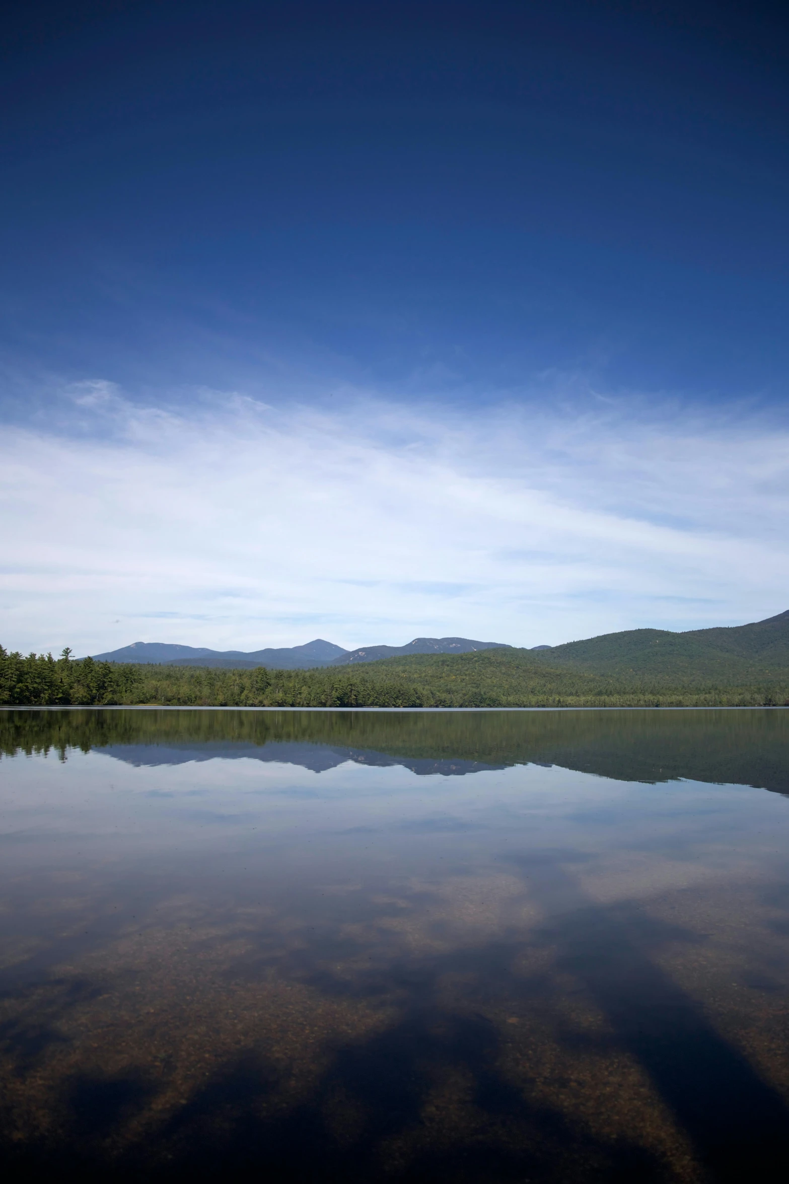 a calm lake surrounded by green trees and mountains