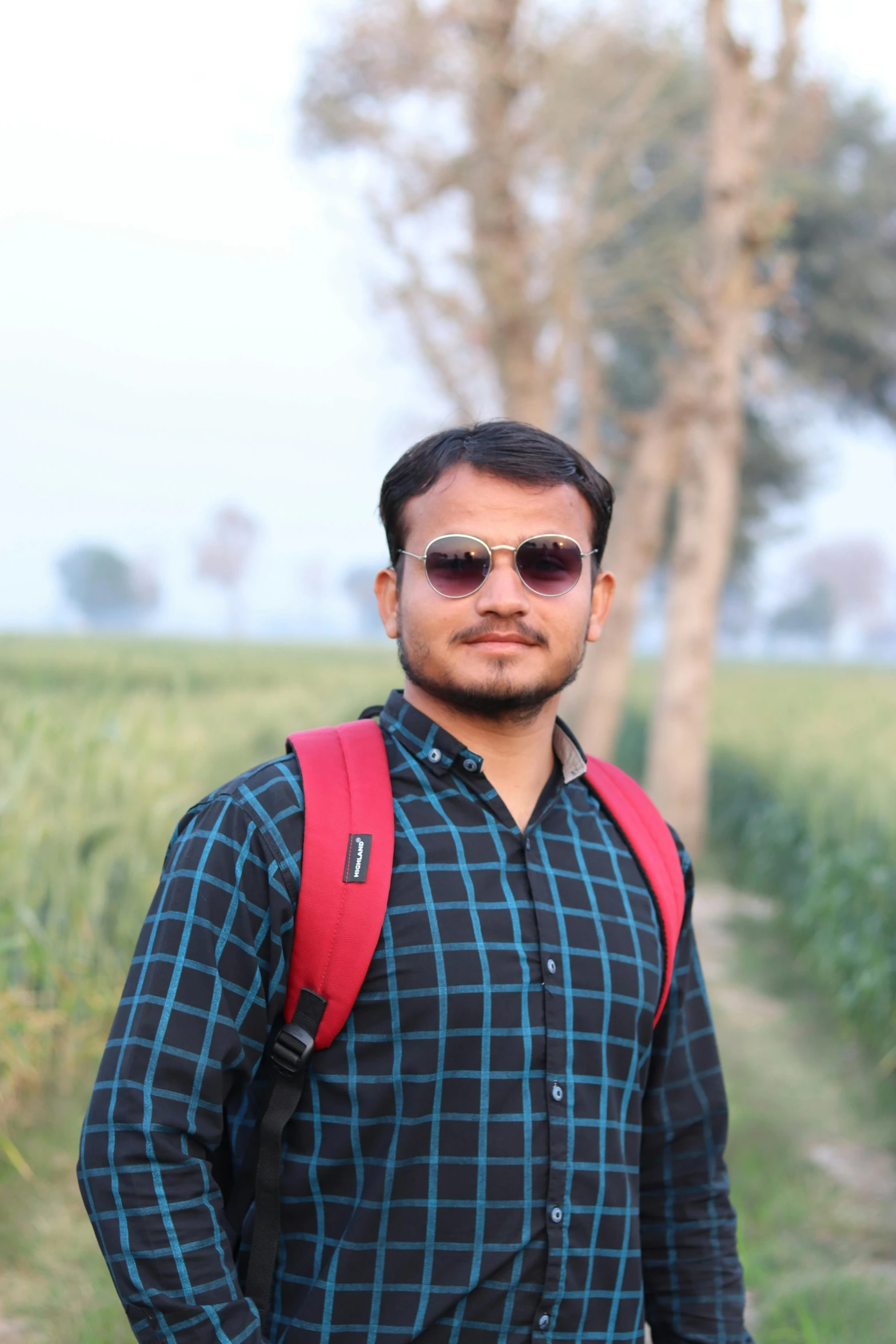 a man standing with his back pack and wearing sunglasses