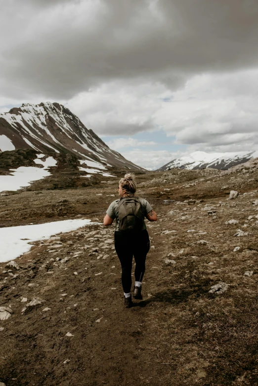 a woman treks on a snowy trail with a snow capped mountain in the background