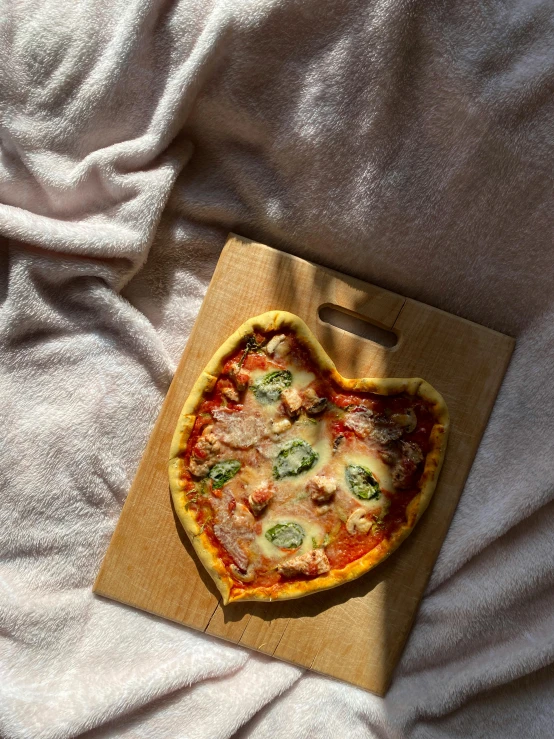 a heart shaped pizza sitting on top of a wooden  board