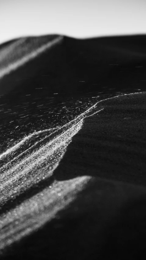 a small wave hitting the beach in black and white