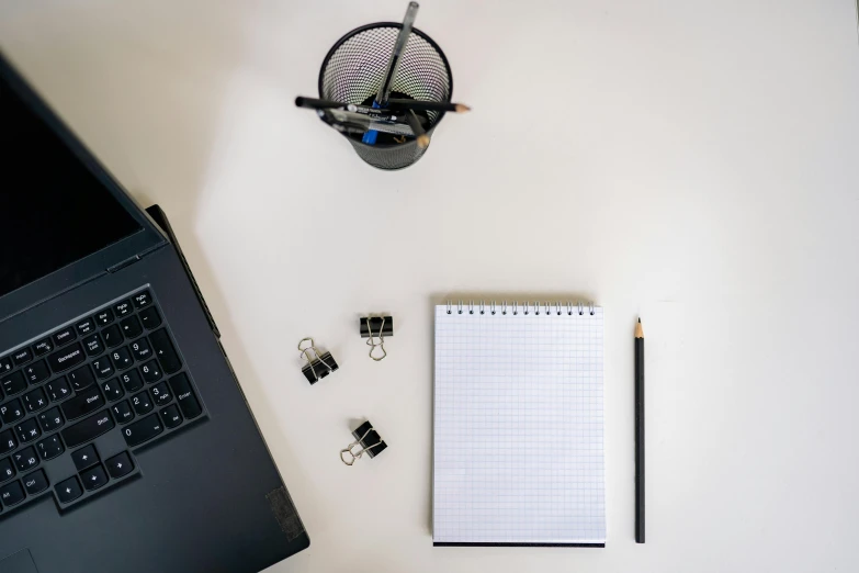 notebook with paper and pen next to a laptop