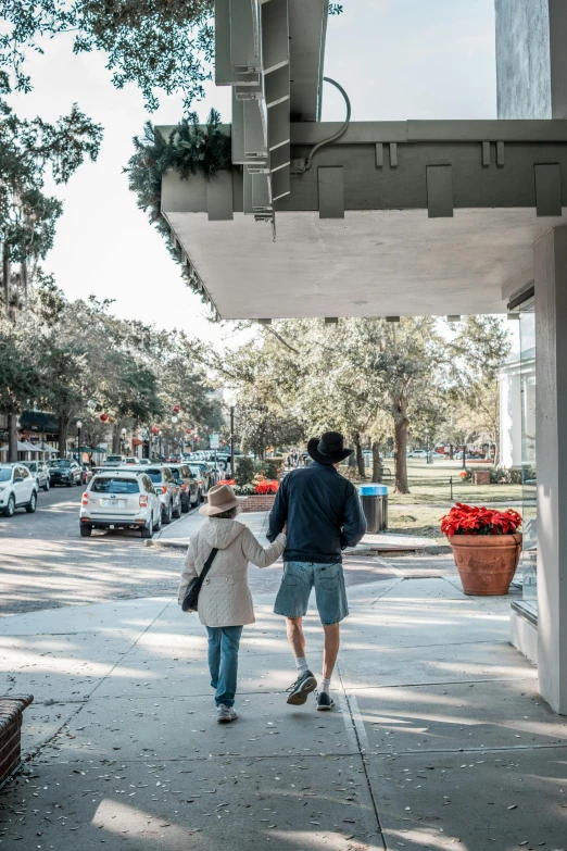 a man and woman walk down the sidewalk