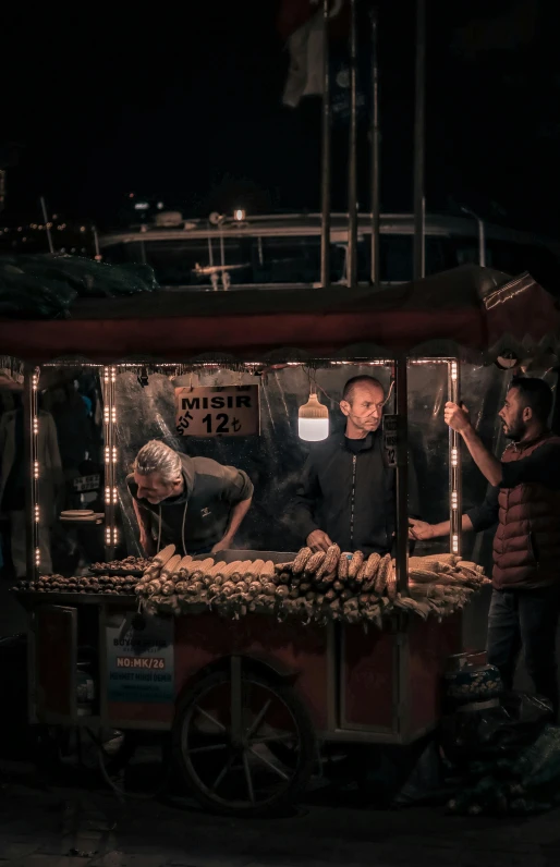 an old fashioned food cart with people standing around it