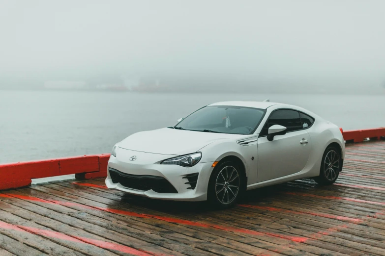 a white sports car parked on a dock next to the ocean