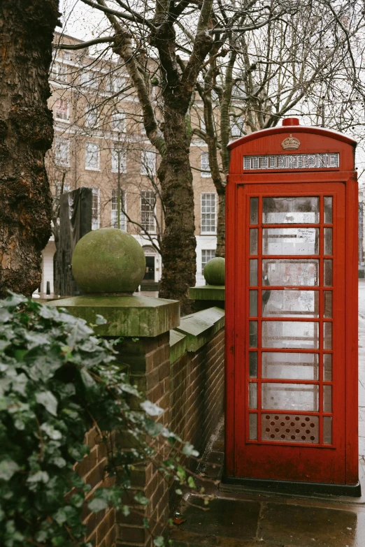 a red telephone booth next to a stone wall