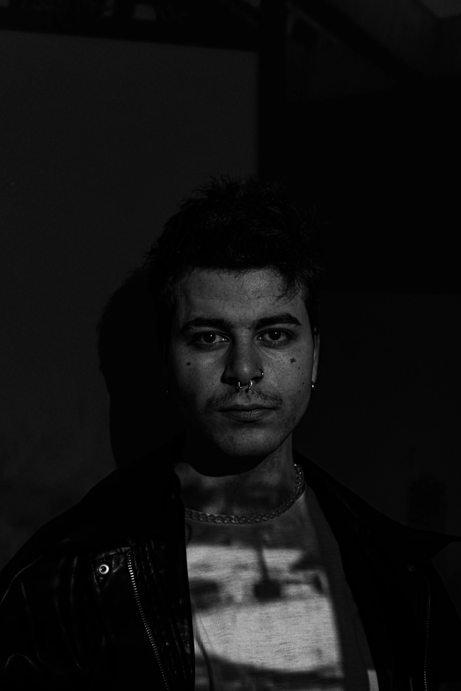 a young man with piercings wearing a leather jacket