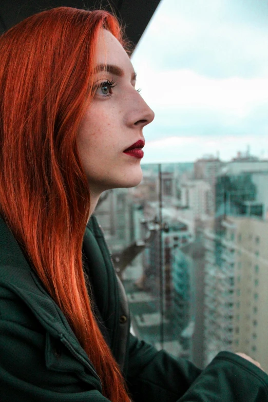 a young woman with red hair looking out a window