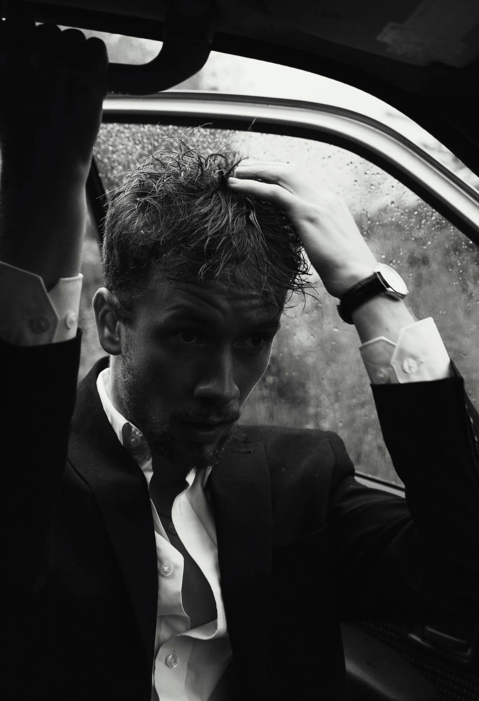 a man in a suit sitting in the backseat of a car