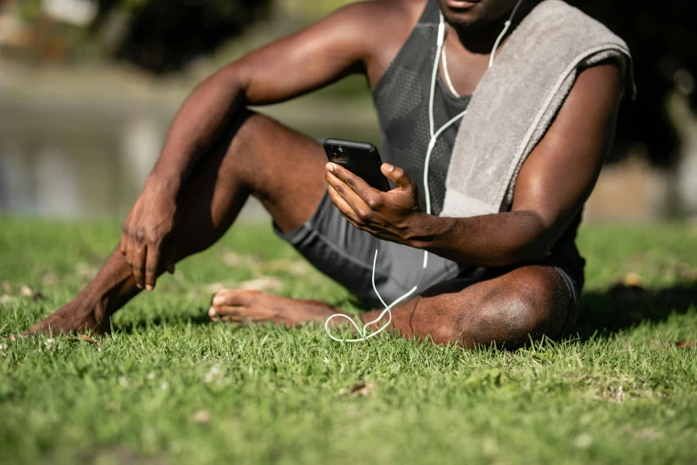 man sitting on grass with headphones in hand