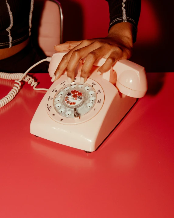 the hands on an old style pink telephone