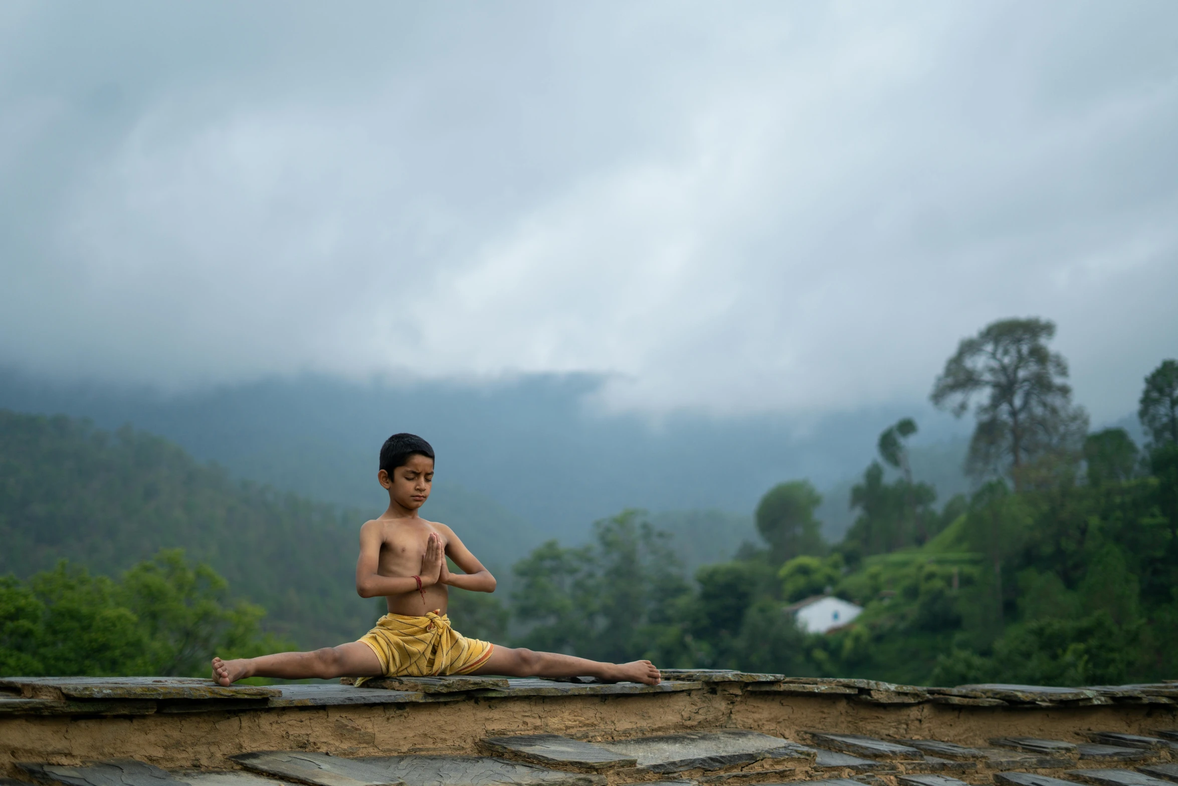 a man sits on a ledge in the middle of a valley