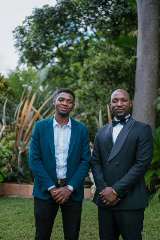 two males are dressed in nice suits and have a smile