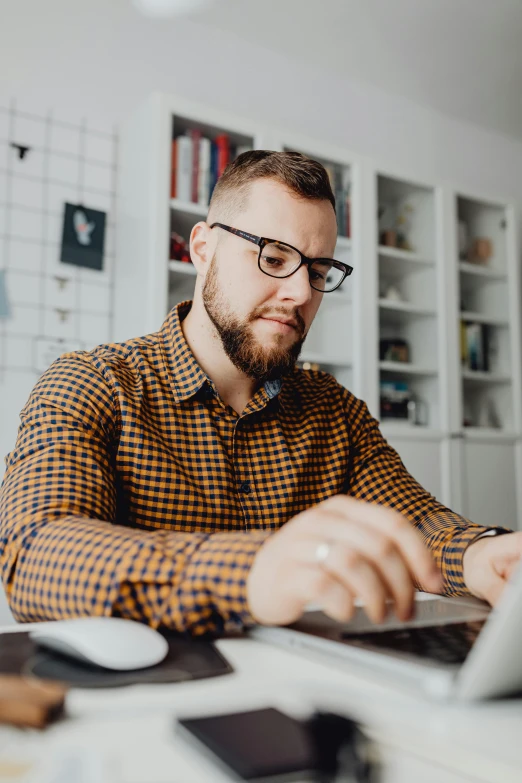 man with beard and glasses working on laptop