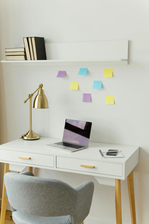 there is a small white desk with a lap top