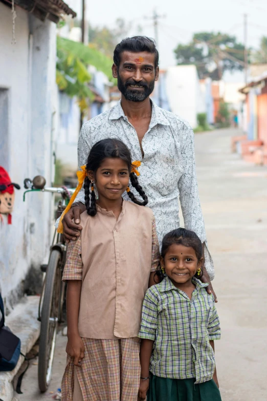 a man stands with two children and smiles