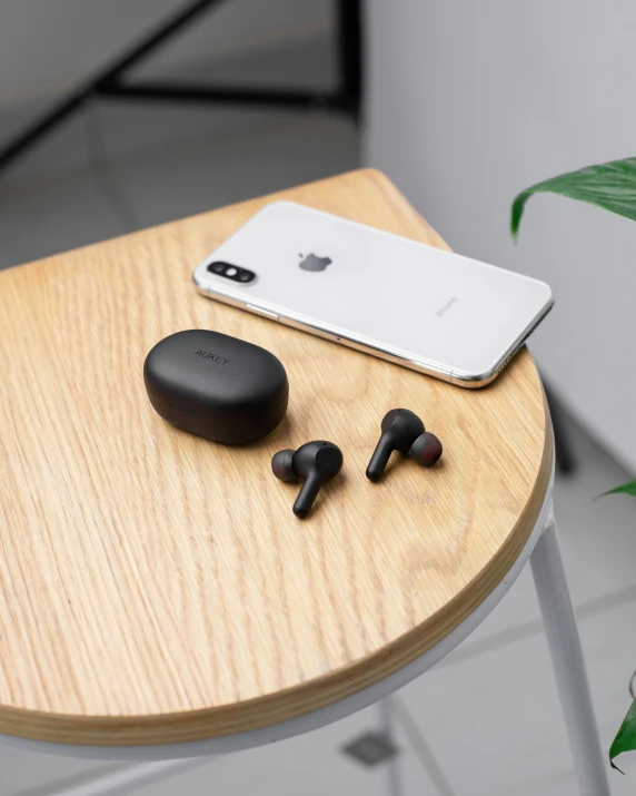 a wooden table with an iphone, earphones and a phone sitting on top