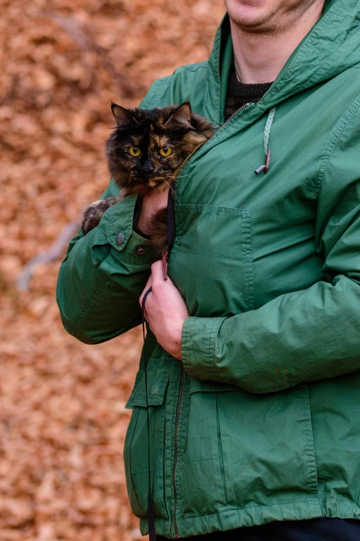 a man in a green coat holding a cat