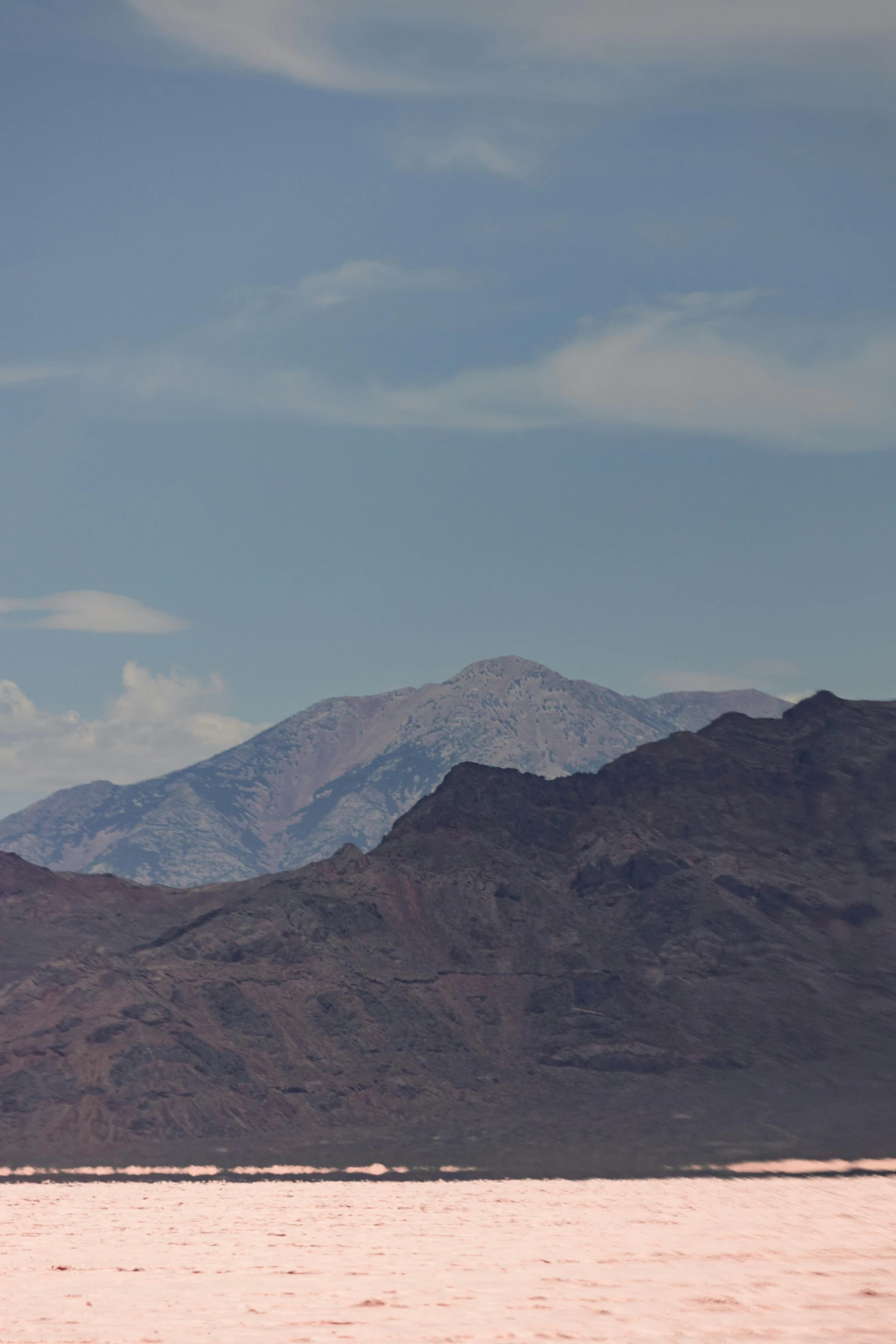 a lone bird flies high above the mountains