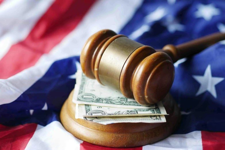 the judge's gavel on top of the us flag is covered by money