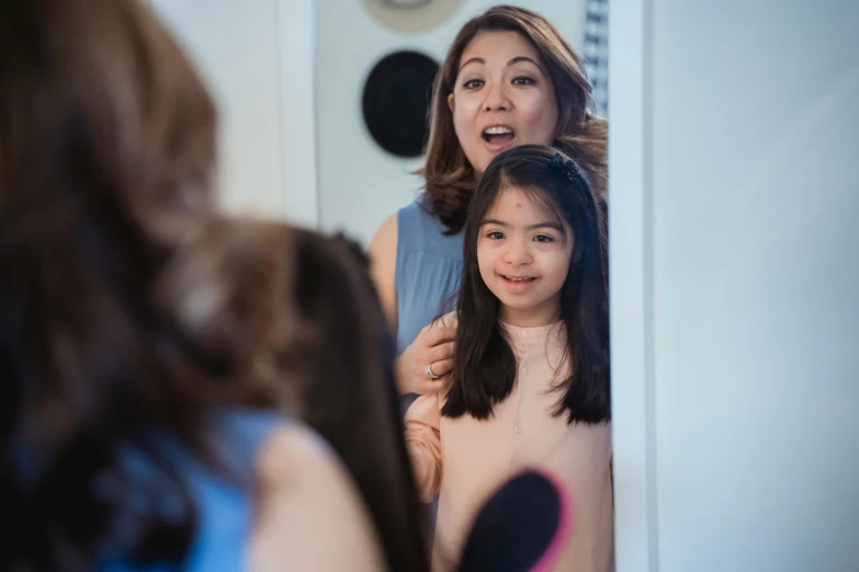 a woman blow drying another's hair behind a mirror