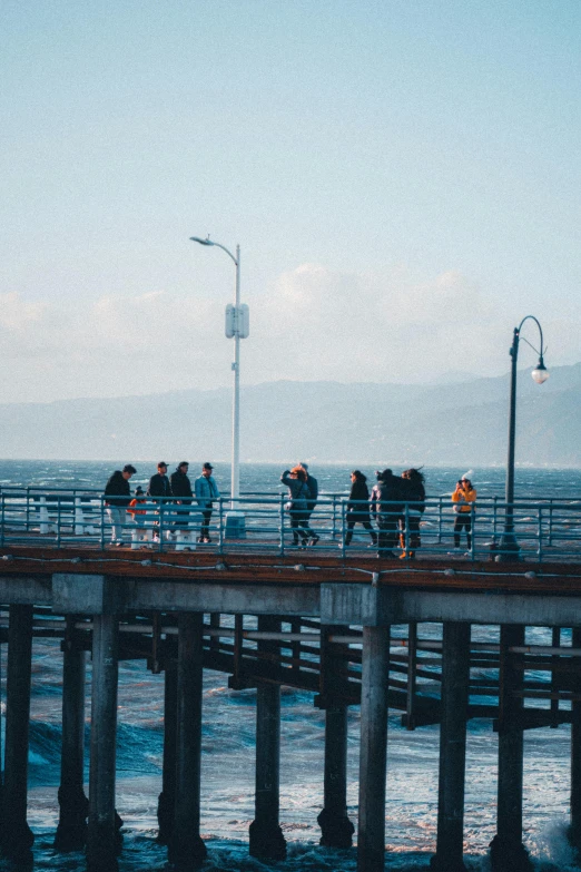 a group of people walking on a bridge near the ocean