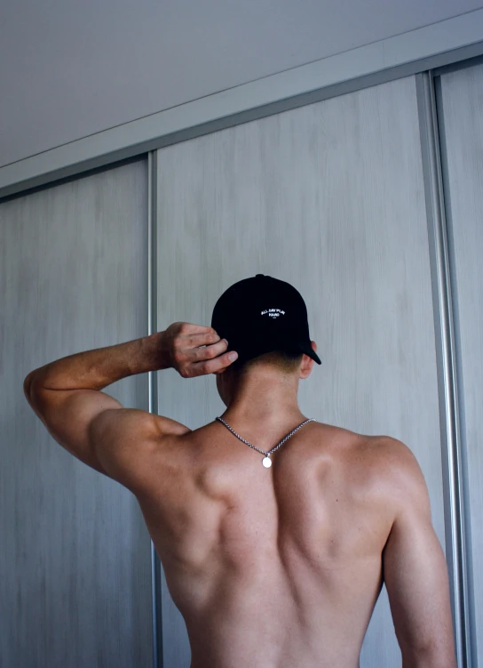 man wearing an unoned shirt stands by a closet