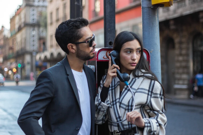 a man and woman standing next to a pole in the street