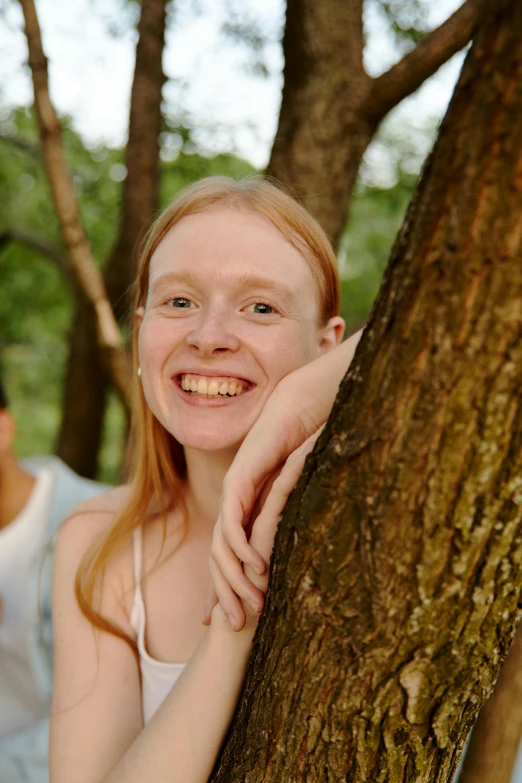 a woman is posing by a tree outside