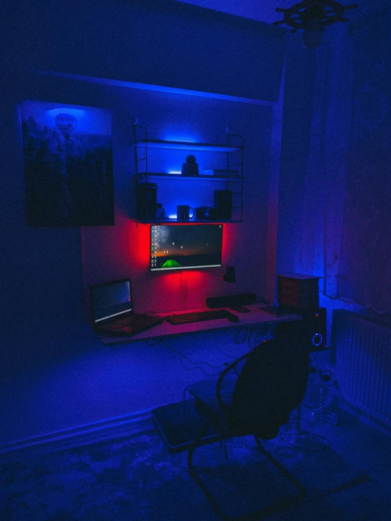 a dark room with a television, chair and a computer desk