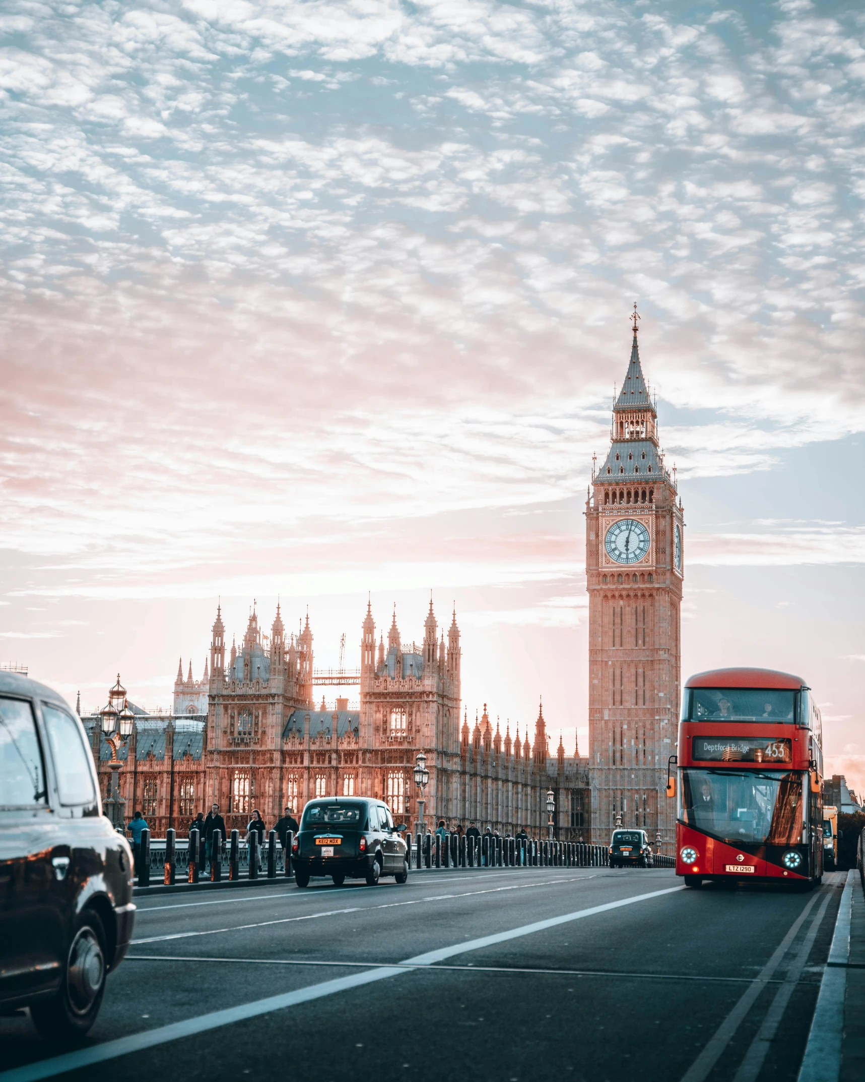 big ben is in the background as cars drive down the road