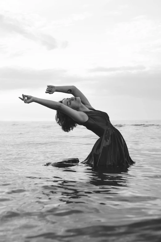 woman with arm extended, in ocean on beach with her arms outstretched