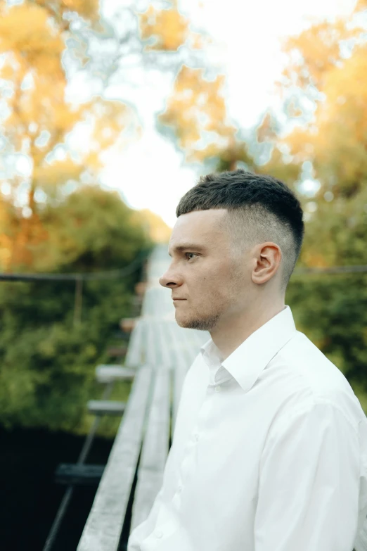 a man in a white shirt is standing near a fence