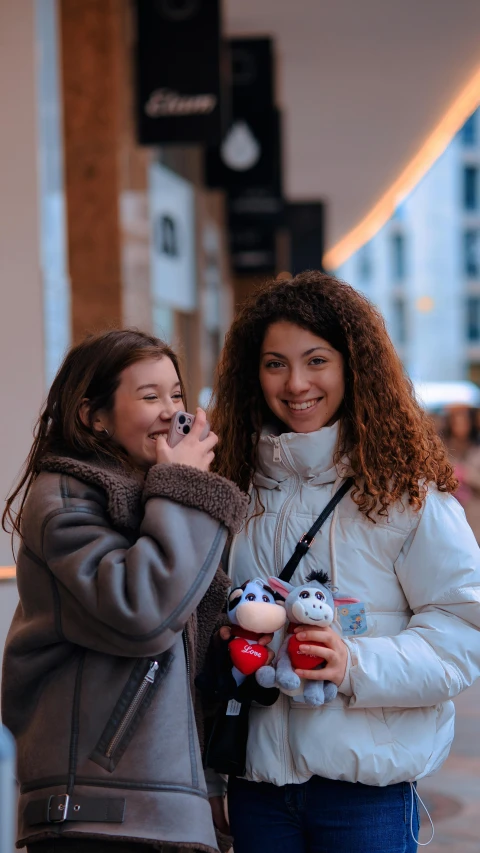 two women standing together on the sidewalk talking