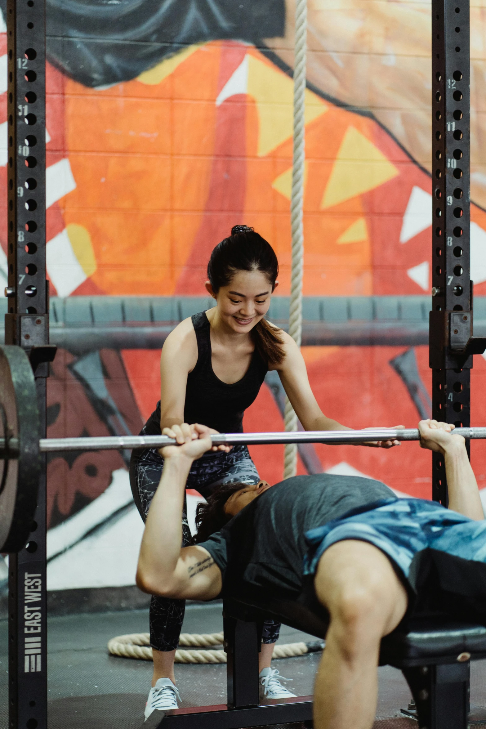 a man and woman squat on a bench at a gym