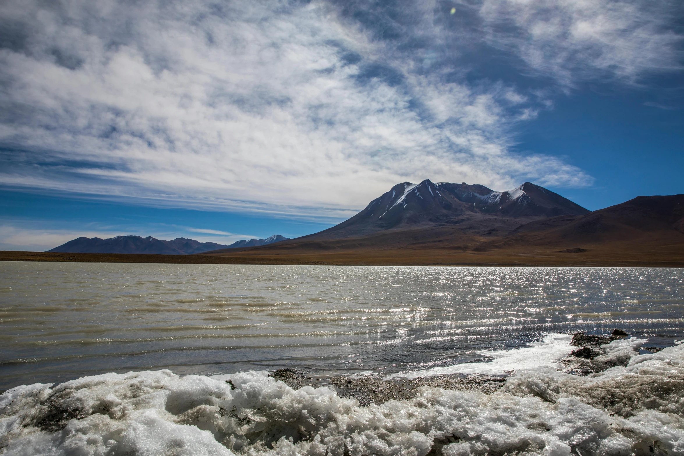 a body of water surrounded by mountains in the distance